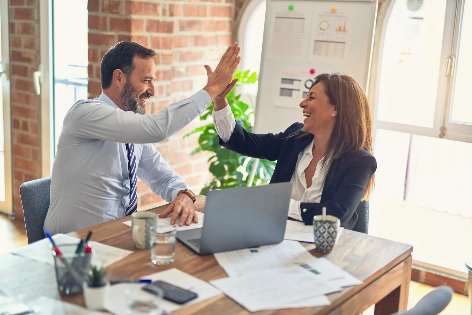 Two colleagues high-fiving at a desk
