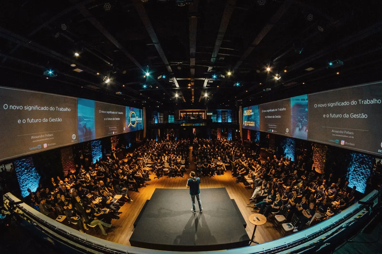 Keynote speaker on a lit stage in front of a full auditorium