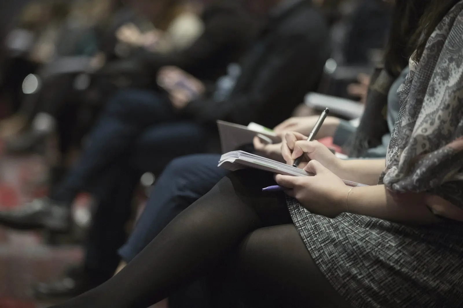 Participant care își notează idei într-un carnet în timpul unei prezentări